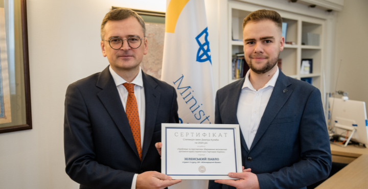 Two men holding a certificate
Description automatically generated
